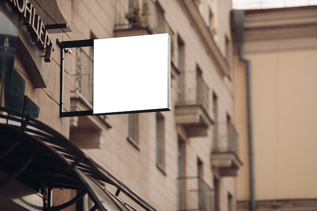 A small billboard, mockup on a building in the city center with a cafe advertisement