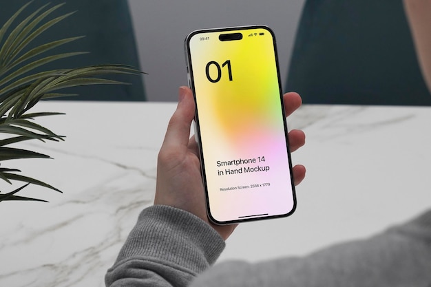 Marbel テーブルに座っているスマートフォン 14 のモックアップ
