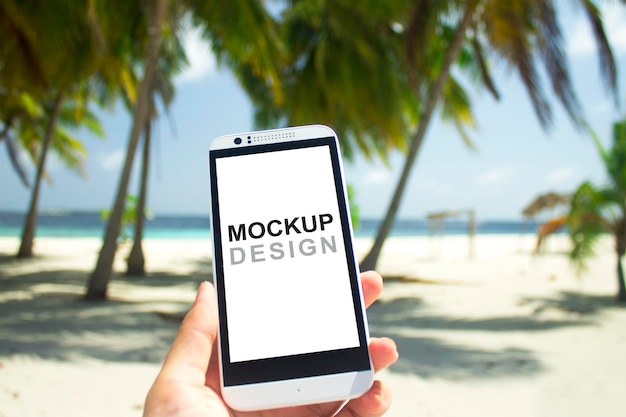 Smartphone mock-up con tenersi per mano, spiaggia, sabbia bianca