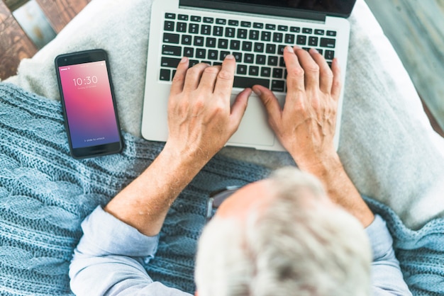 Mockup di smartphone per la presentazione di app con l'uomo che utilizza computer portatile