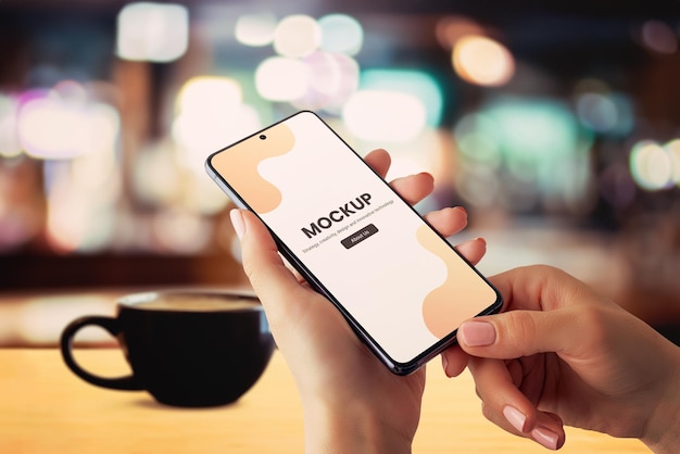 PSD smartphone mockup in hands with coffee mug on table