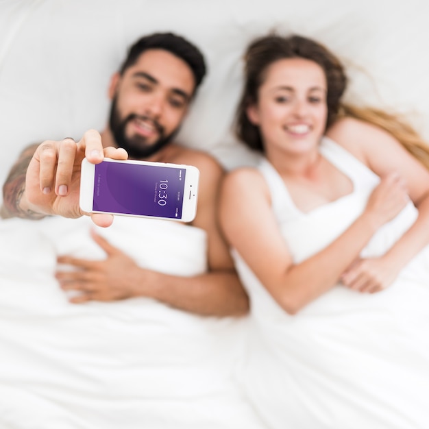 PSD smartphone-mockup met paar in bed