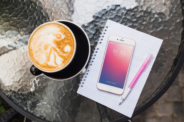 Mockup di smartphone sul tavolo con cappuchino