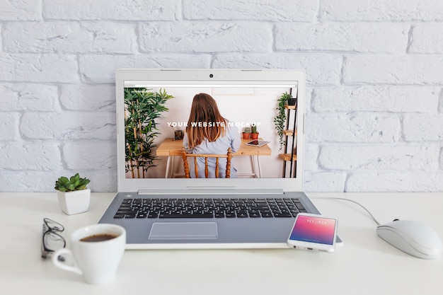 Smartphone mockup with laptop and workspace concept