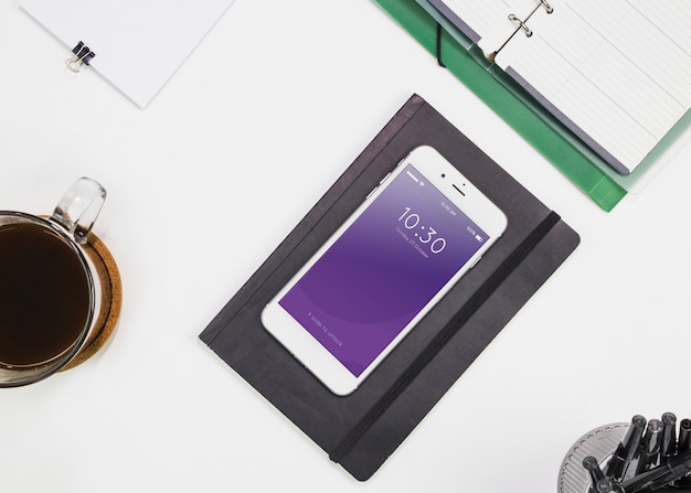 PSD mockup di smartphone con materiali per ufficio sul tavolo