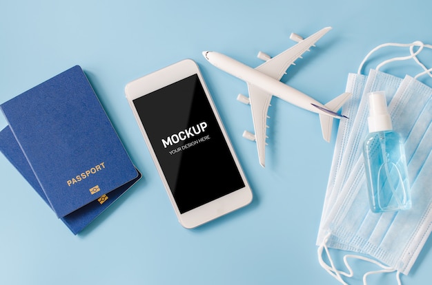 Smartphone con modello di aereo, passaporti, maschera e disinfettante