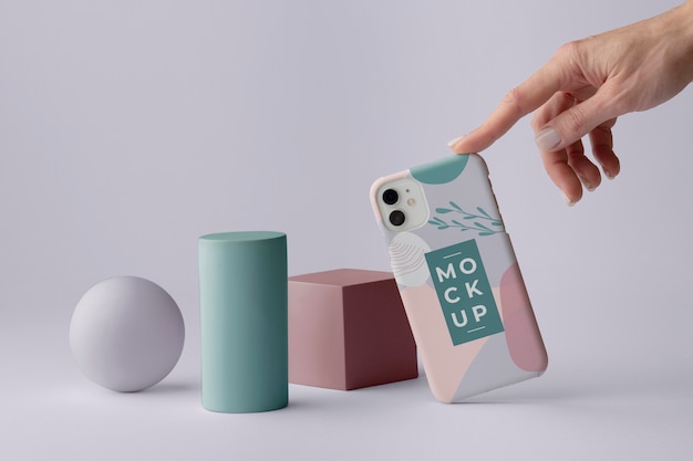 smartphone with mock-up phone case and hand next to geometric shapes