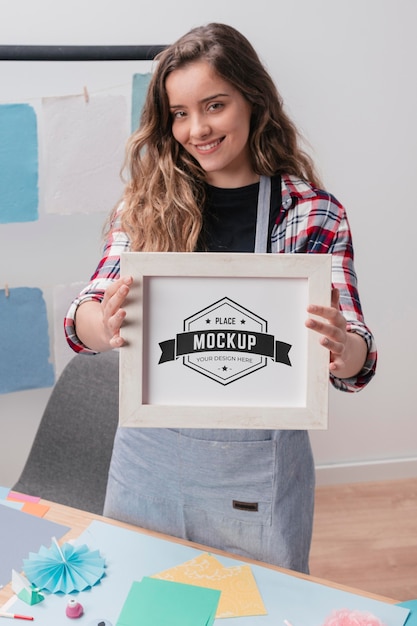 PSD smiley female artist holding mock-up frame