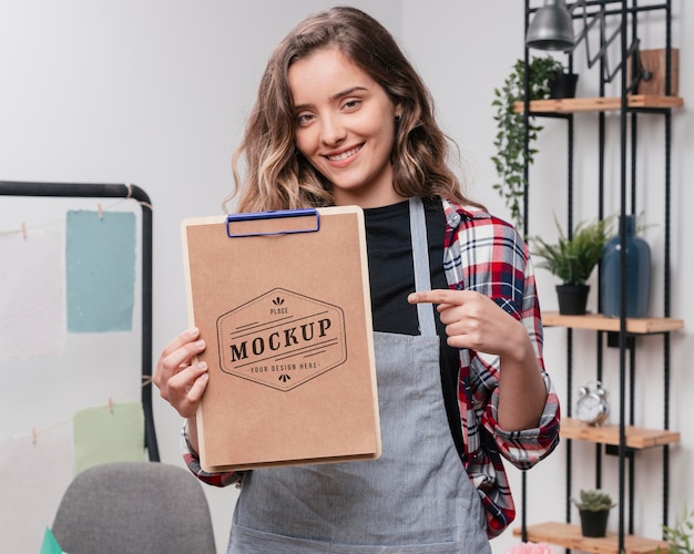 PSD smiley female artist holding mock-up notepad and pointing at it