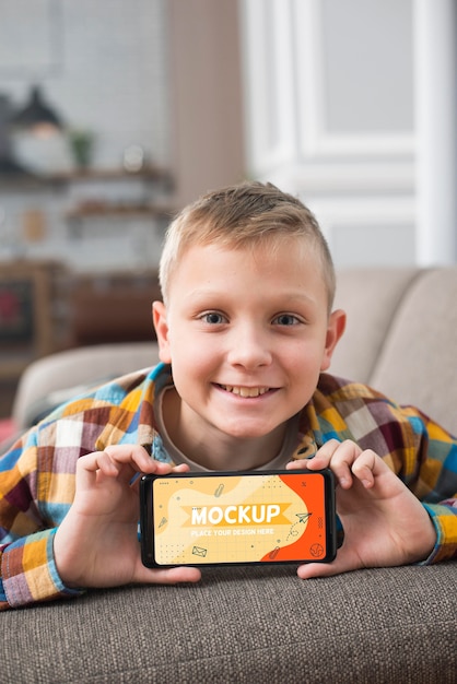 smiley kid on couch holding smartphone