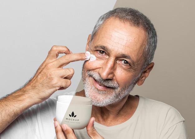 smiley senior man holding cream container