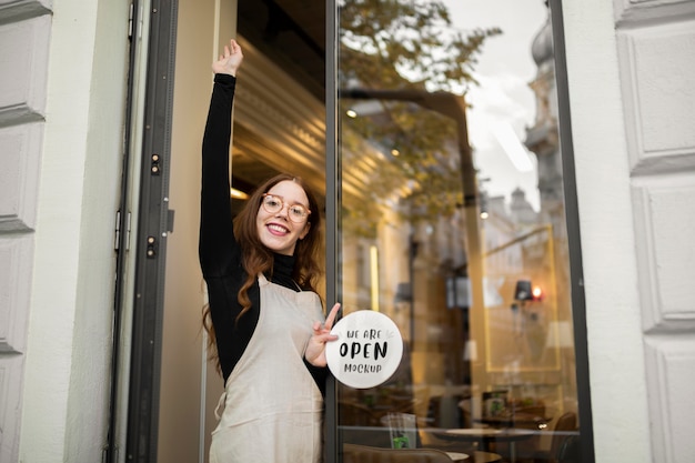 PSD smileyvrouw die bij een restaurant werkt dat naast de deur staat