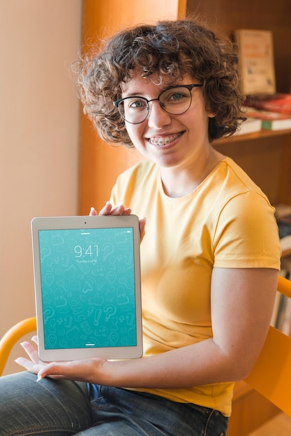 PSD smiling woman holding tablet mockup in library