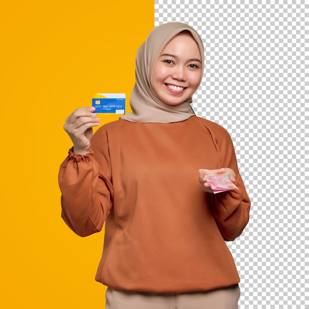 Smiling young asian woman in orange shirt holding money banknotes and showing credit card