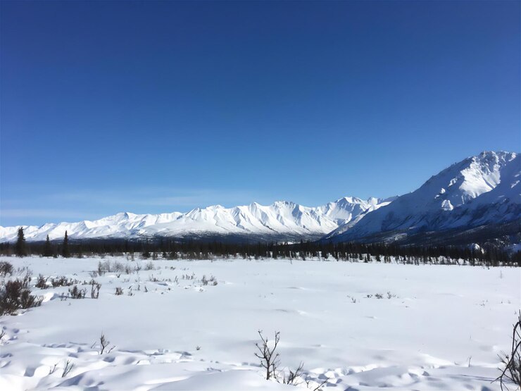 PSD snow-covered mountains under a bright blue sky