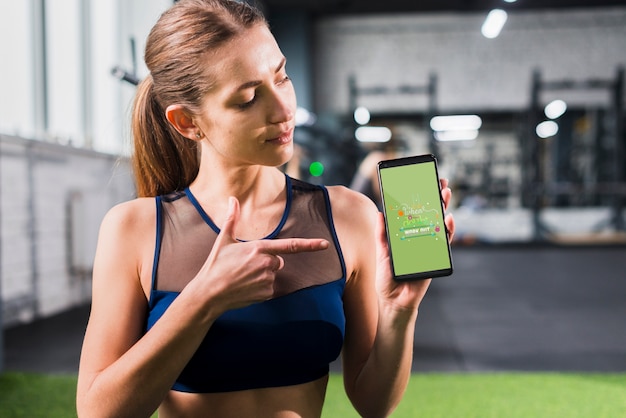 PSD sporty woman pointing at smartphone mockup