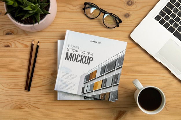 PSD square book mock-up on wooden desk with stationery