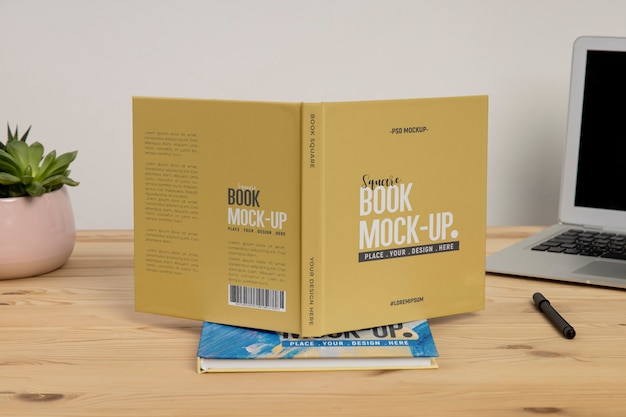 PSD square book mock-up on wooden office desk with laptop and eyeglasses