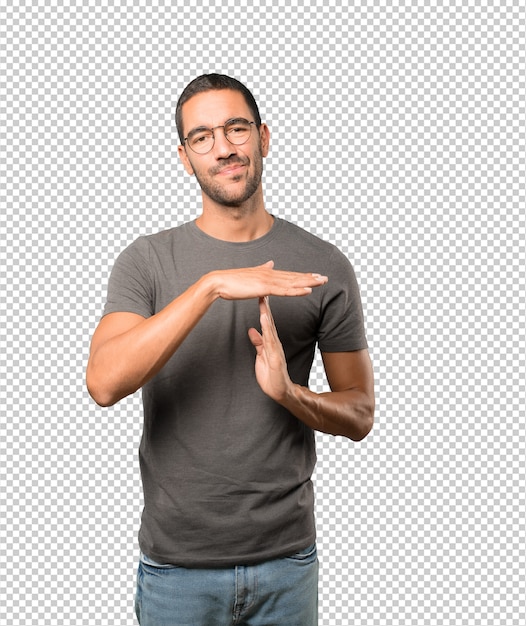 Stressed young man making a time out gesture with his hands