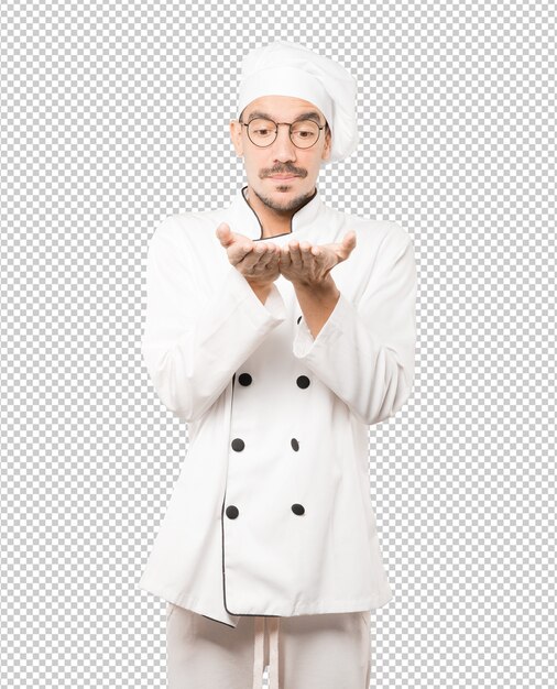 Surprised young chef holding something with his hand