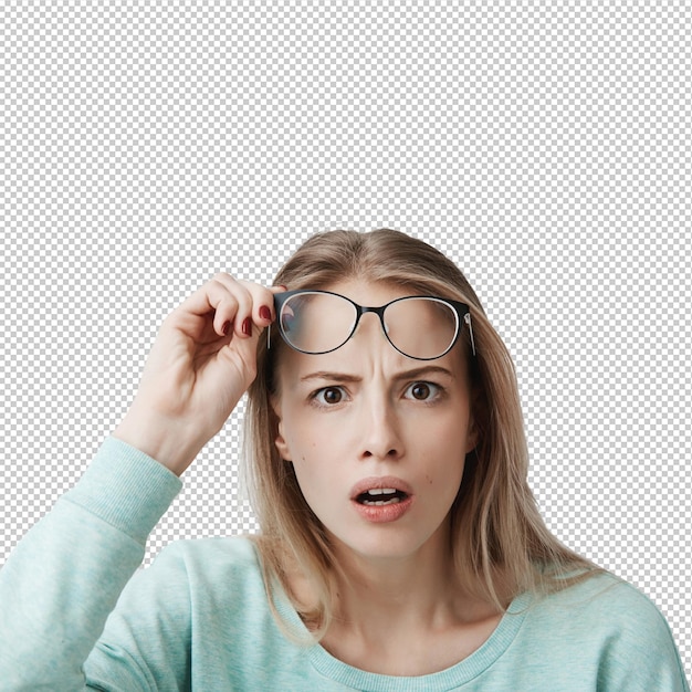 Surprised young female model with long blonde hair wears glasses and blue longsleeved shirt looks with terror
