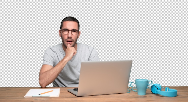 PSD suspicious young man sitting at his desk