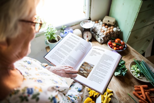 PSD szczęśliwa starsza kobieta czyta książkę kucharska