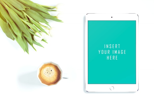 Tablet su sfondo bianco con i fiori e il caffè imitazione