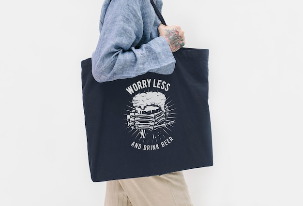 PSD tattooed woman in a blue linen shirt holding a black tote bag