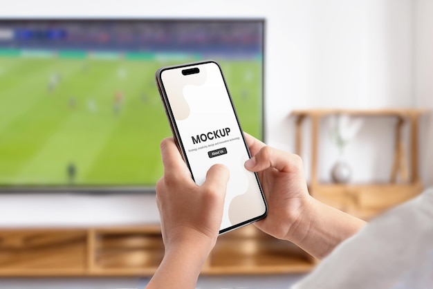 PSD telefoon mockup in handen voor de tv met voetbalwedstrijd