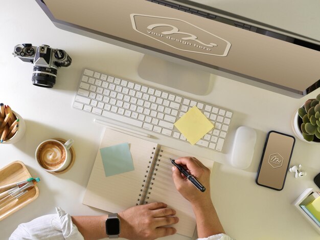 Top view of businessman hand writing on blank notebook mockup