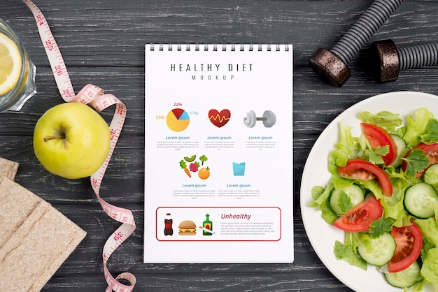 Top view of fitness notebook with plate of salad