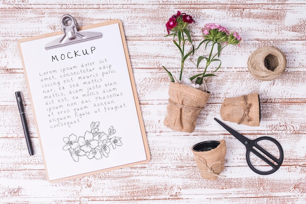 Top view gardening tools and flowers with clipboard mock-up