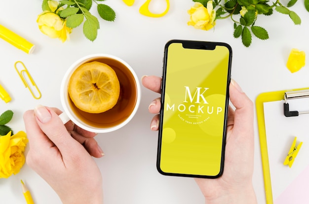 PSD vista dall'alto mani che tengono smartphone mock-up con tè