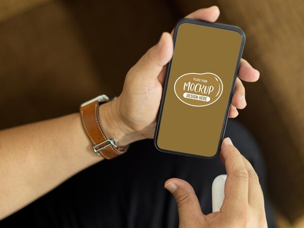 Top view of a man sitting on the couch and holding smartphone mockup