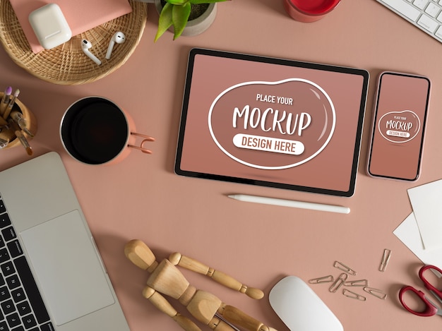 Vista dall'alto di mock up tablet e smartphone sul tavolo rosa con accessori e forniture