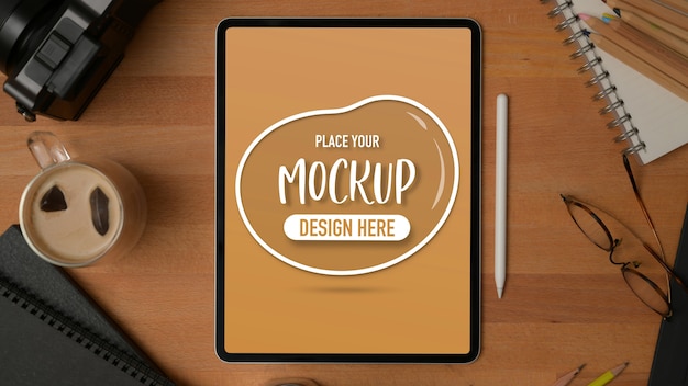 Top view of mockup digital tablet on wooden table with stationery