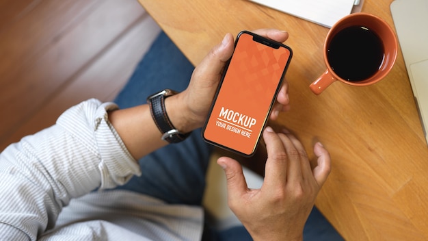 スマートフォンのモックアップを使用して男性の手の上面図