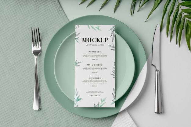 Top view of spring menu mock-up on plates with leaves and cutlery