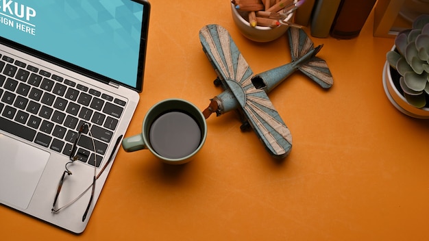 PSD Вид сверху на рабочее пространство с макетом ноутбука, кофейной кружкой, украшениями в домашнем офисе