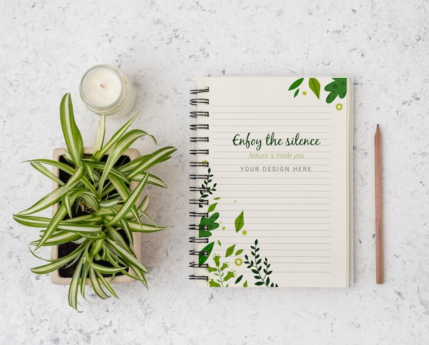 Top view plant surrounded by notepad with mock-up