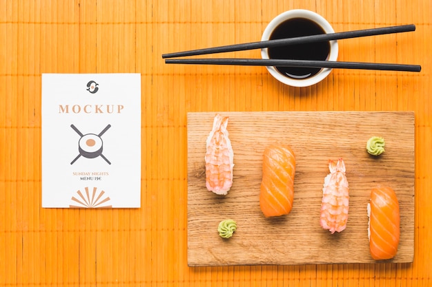 Top view of sushi on chopping board with soy sauce and chopsticks