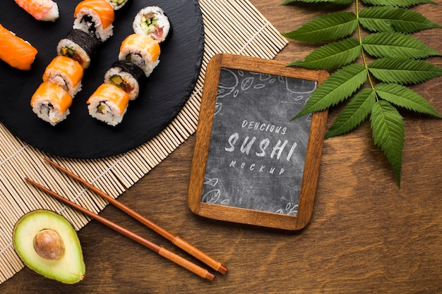 Top view of sushi variety with blackboard and avocado