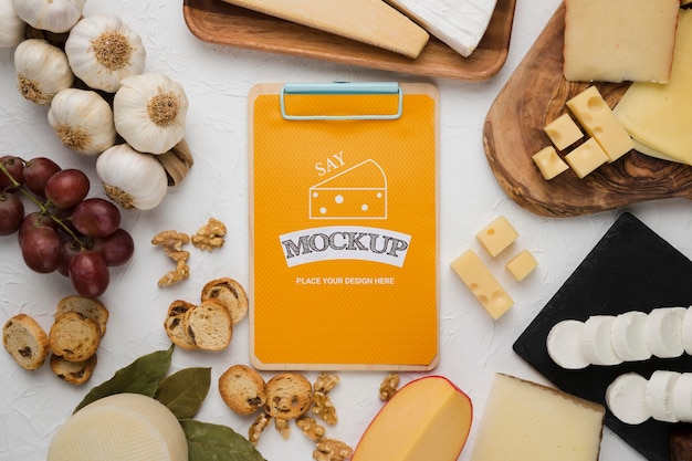 Top view of variety of cheese with notepad and garlic