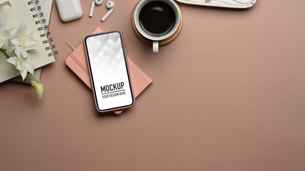スマートフォンのモックアップ、ノートブック、アクセサリーを備えたワークスペースの上面図