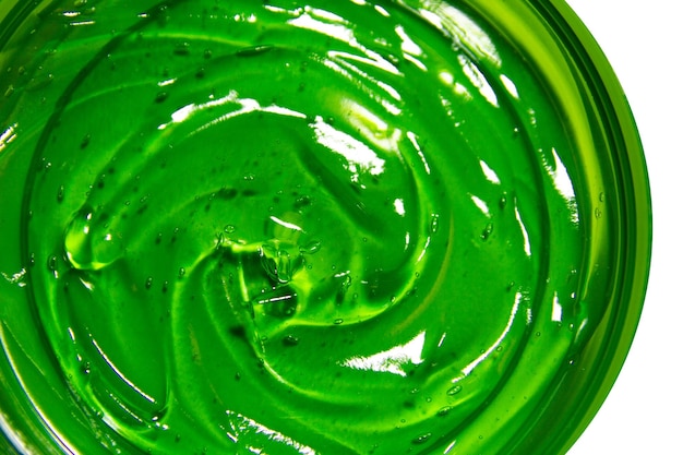 Transparent green cosmetic gel in a round jar on an empty background