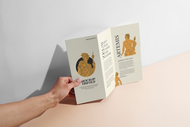 Trifold brochure mock-up held by person in hand