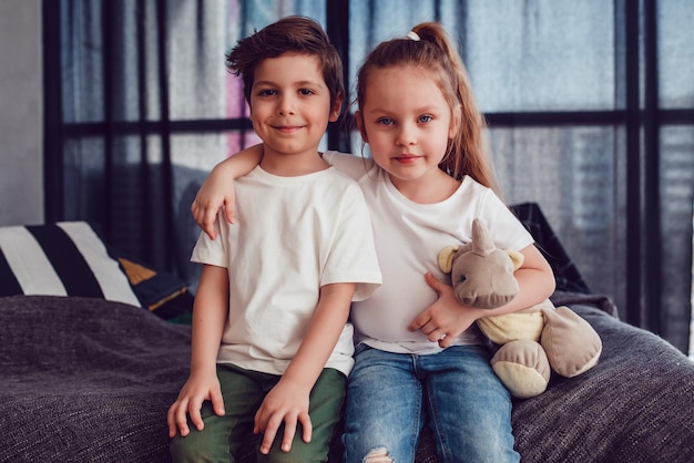 Twee schattige kinderen poseren samen glimlachend en omhelzen elkaar