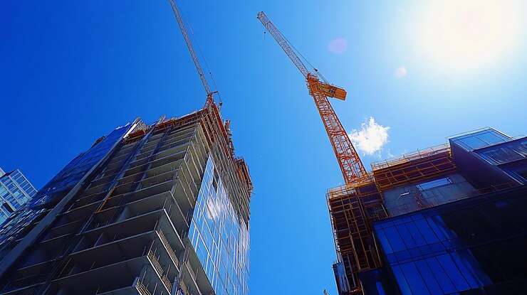 PSD two highrise buildings under construction with cranes against a clear blue sky