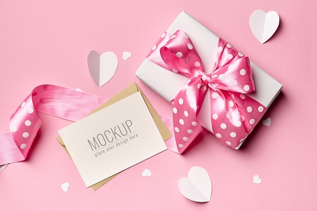 Valentijnsdag kaart mockup met geschenkdoos en papieren hartjes op roze